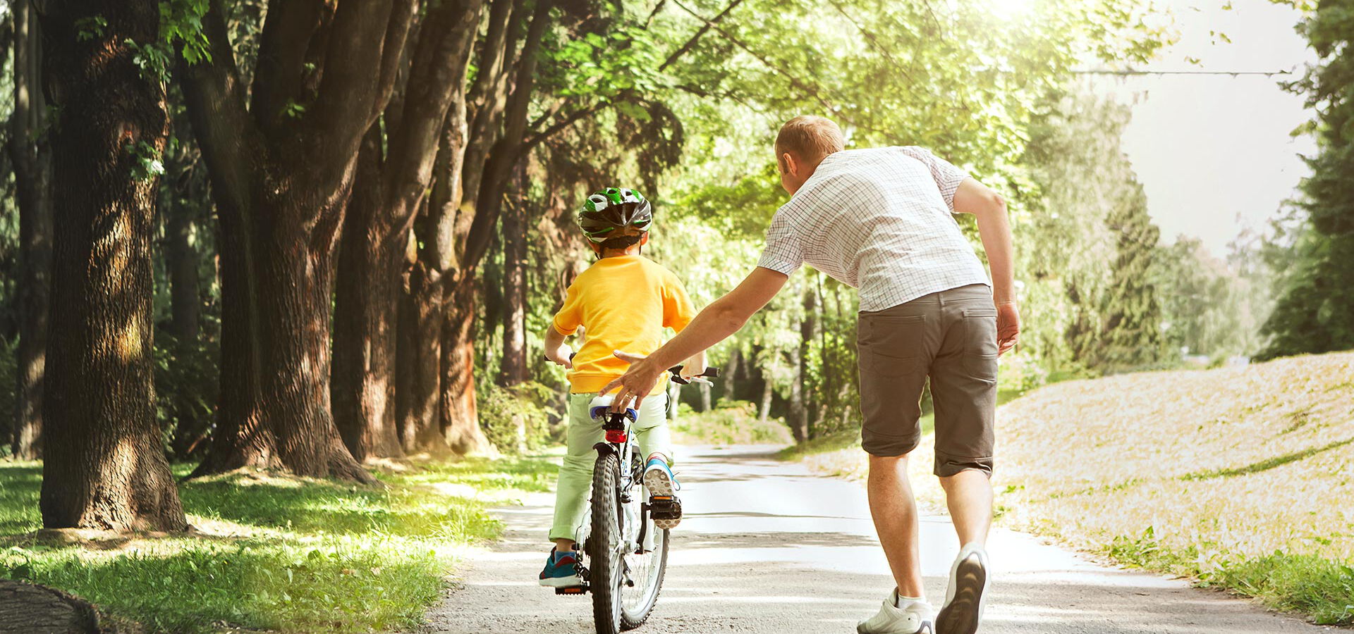 Vater hilft seinem Kind beim Fahrradfahren